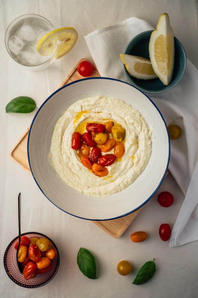 Whipped white feta dip with roasted tomatoes on a pale plate — illustrative stock photograph