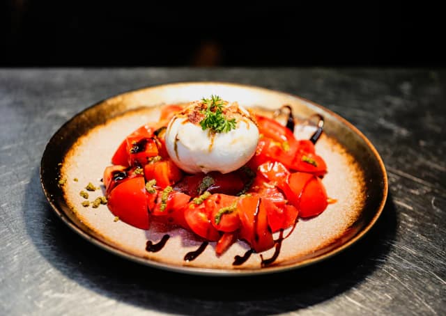 Burrata cheese with tomatoes on a dark plate — illustrative stock photograph