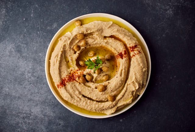 Creamy hummus garnished with herbs and oil — illustrative stock photograph