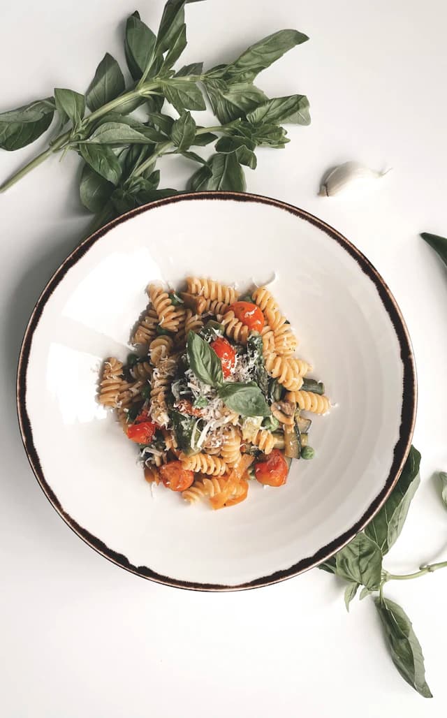 Fusilli spirals with green leaves and grated cheese — illustrative stock photograph