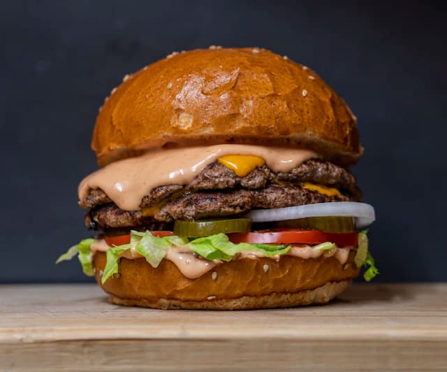 Beef burger with melted cheese, onion and green lettuce — illustrative stock photograph