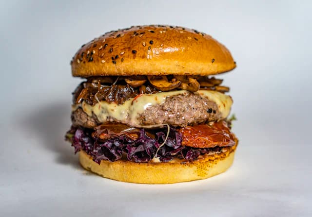 Burger piled with sautéed mushrooms and creamy sauce — illustrative stock photograph