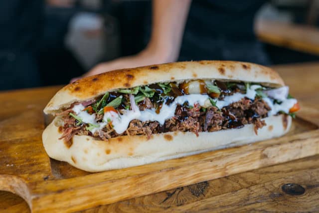 Steak and onion sandwich in a long bread roll — illustrative stock photograph