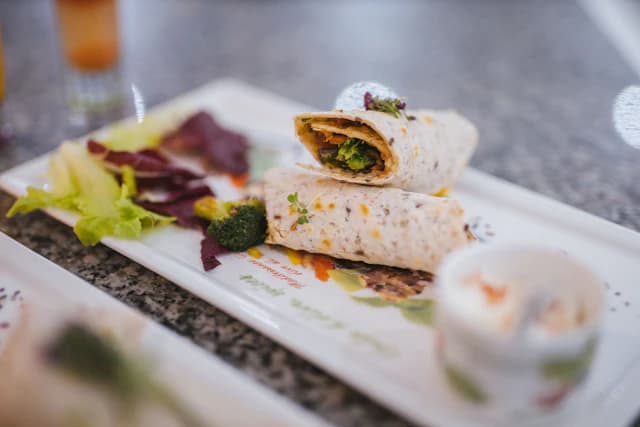 Halved vegetarian wraps with leafy greens on a white plate — illustrative stock photograph