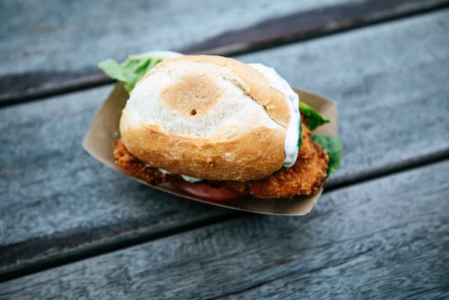 Crispy fish sandwich with greens in a crusty bread roll — illustrative stock photograph