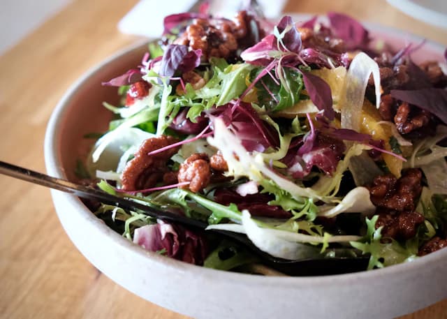 Leafy salad with nuts and slices of fruit in a bowl — illustrative stock photograph