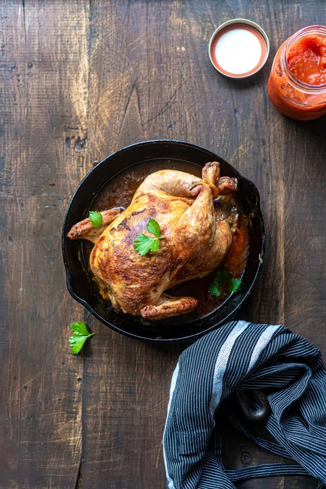 Golden whole roasted chicken in a cast-iron pan — illustrative stock photograph