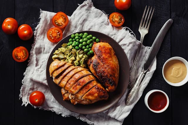 Sliced grilled chicken breast with green vegetables — illustrative stock photograph