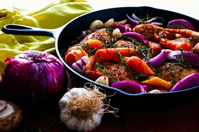 Herbed chicken roasted with carrots and onions in a skillet — illustrative stock photograph