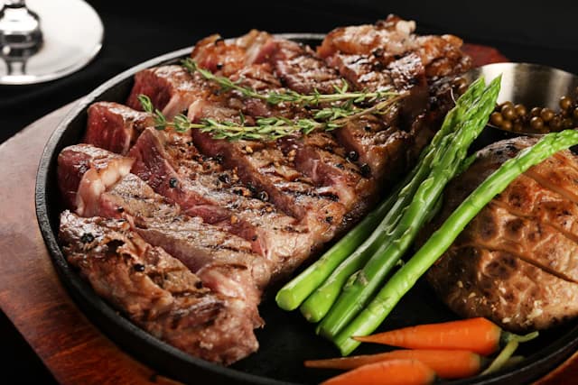 Grilled steak served with green beans on a dark platter — illustrative stock photograph
