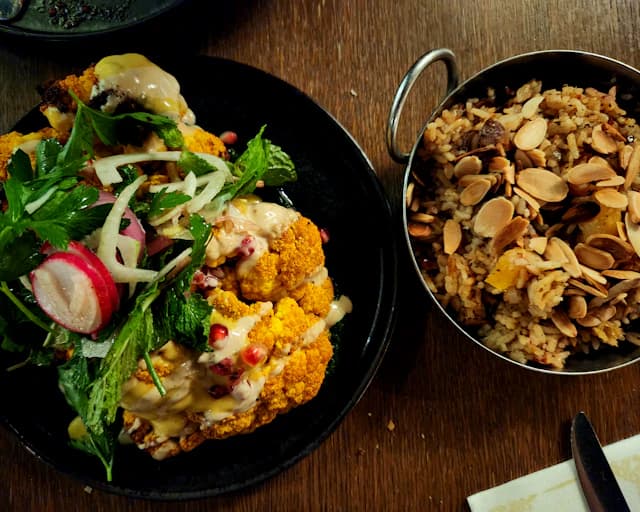 Roasted cauliflower served with greens and grains — illustrative stock photograph