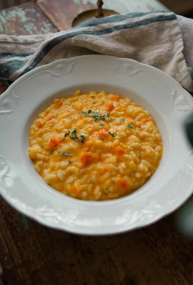 Creamy orange squash risotto in a white bowl — illustrative stock photograph