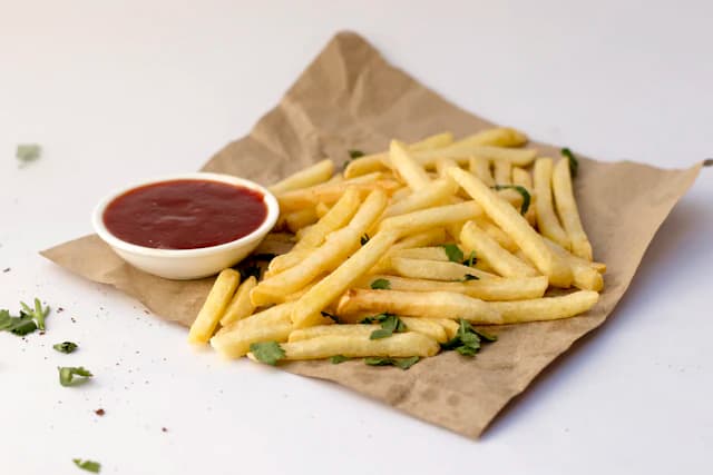 Golden fries in a paper-lined tray with dipping sauce — illustrative stock photograph