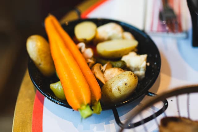Carrots, potatoes and cauliflower on a dark serving dish — illustrative stock photograph