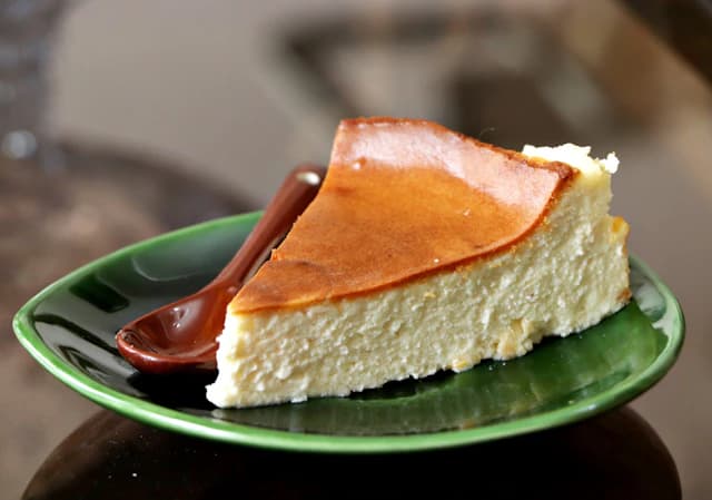 Slice of browned Basque cheesecake on a green plate — illustrative stock photograph