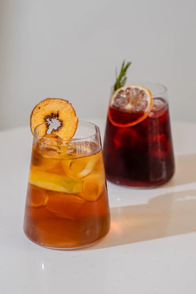 Two orange-coloured citrus drinks with slices of fruit — illustrative stock photograph