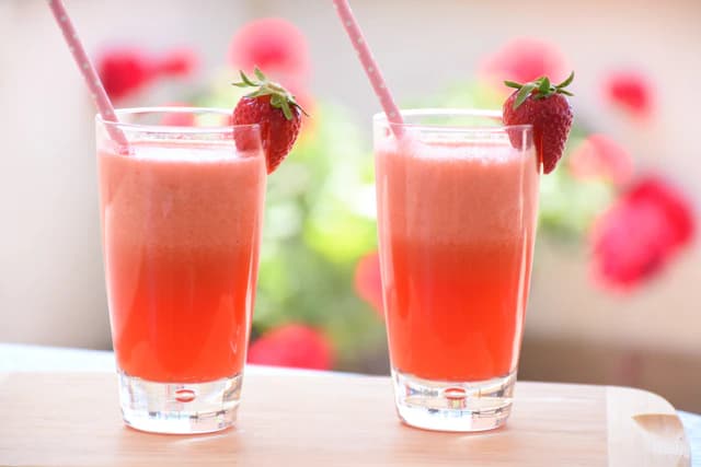 Two glasses of pink strawberry lemonade with fresh strawberries — illustrative stock photograph