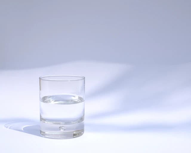 Clear drinking water in a glass against a light background — illustrative stock photograph
