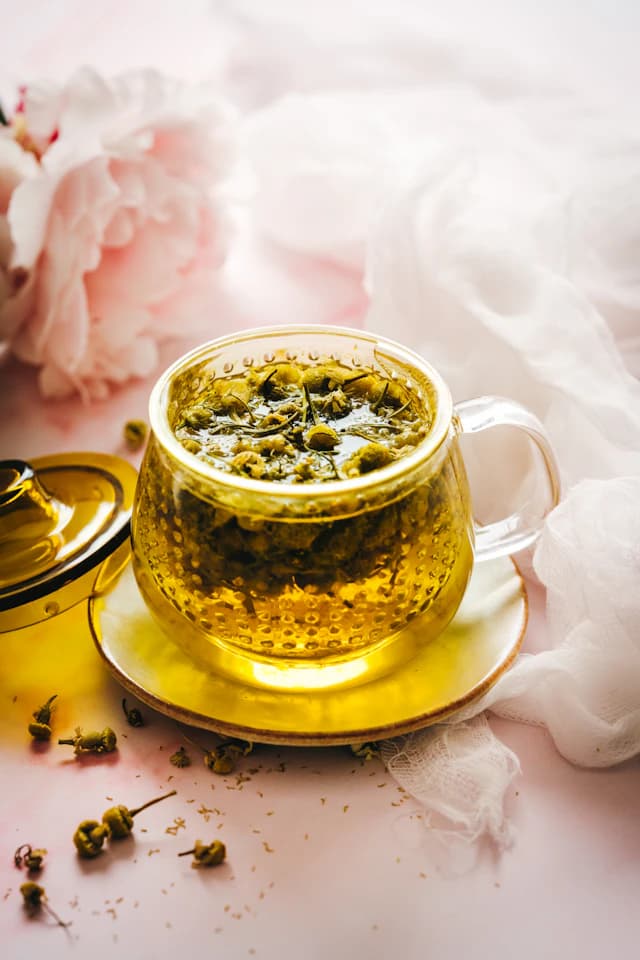 Cup of golden chamomile tea with small white flowers — illustrative stock photograph